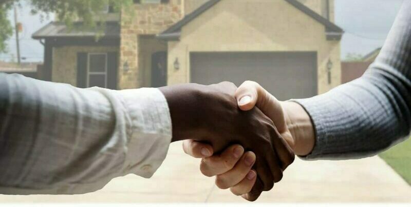 Buyer representation or Seller representation - Realtor and client shaking hands in front of house 