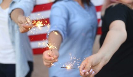 people holding sparklers with US flag in the background