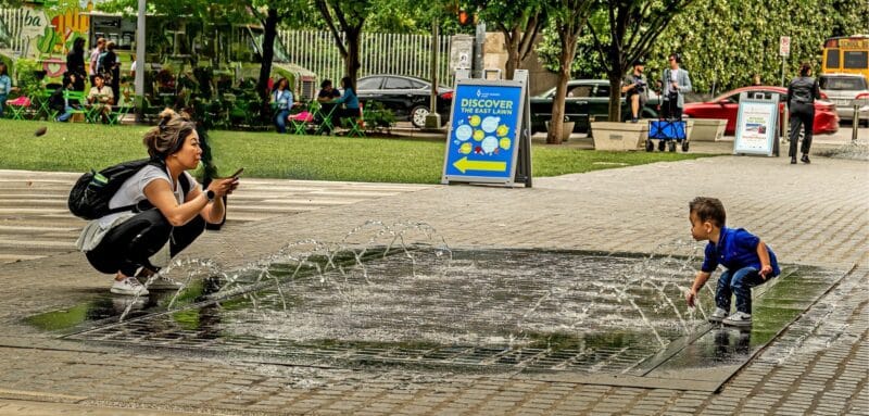 Mother and child playing in a fountain at Katy Trail in Dallas