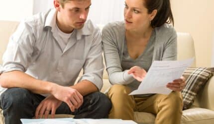 Couple looking at paperwork concerned about scams target new homeowners