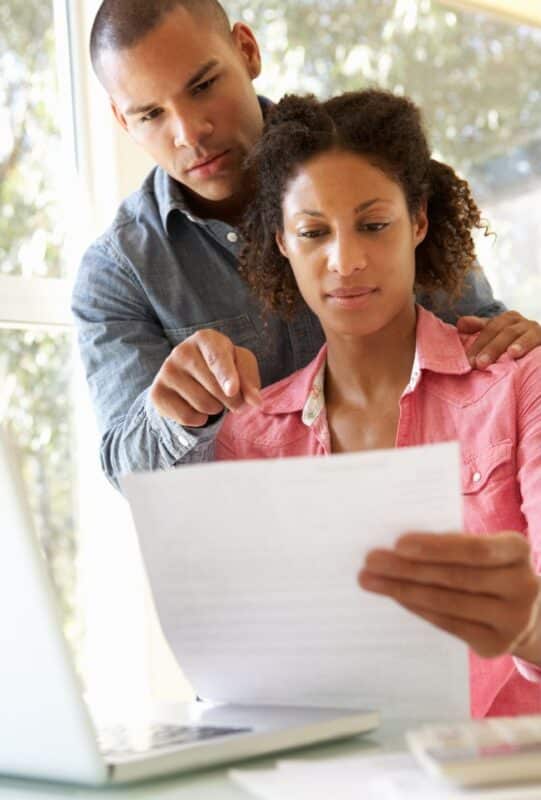 Couple looking at a letter, thinking it's part of scams targeting new homeowners